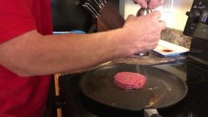 burger on skillet and seasoning